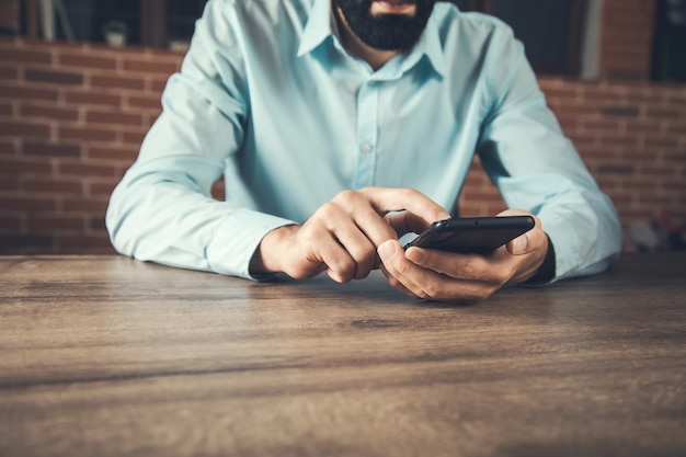 Businessman hand holding smart phone on the table