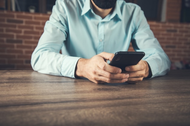 Businessman hand holding smart phone on the table