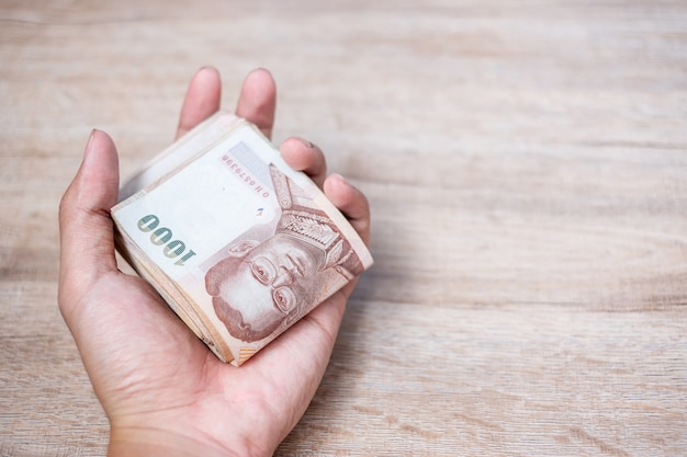 Businessman hand holding Thai Baht banknote stack. 