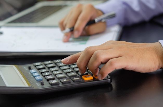 Businessman hand pressing a calculator Business, finance, tax and investment concept.