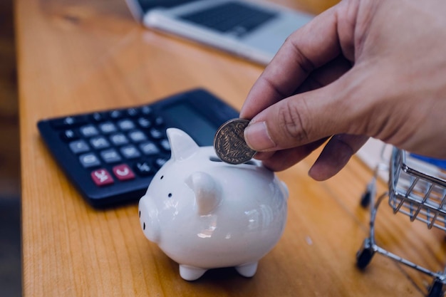 Businessman hand putting coin in piggy bank Saving money concept business finance and investment