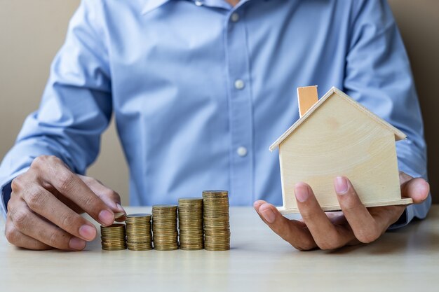 Businessman hand putting golden coin on growing money stairs 