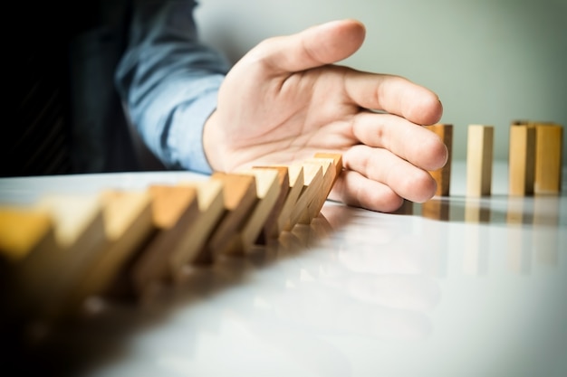 businessman hand stop dominoes continuous toppled or risk with copyspace