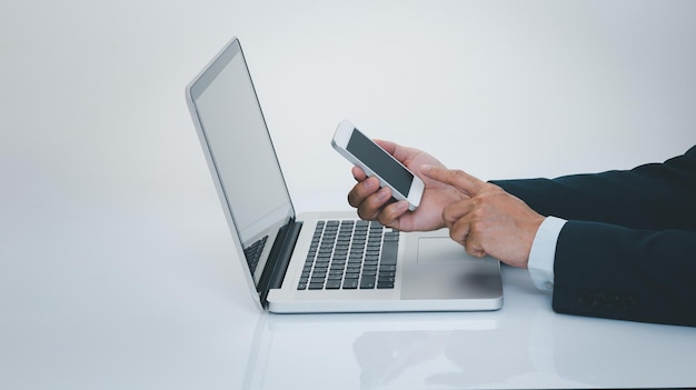 Businessman hand using smartphone with laptop computer Business and technology concept