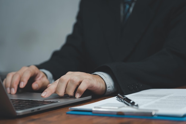 Businessman hand work on keyboard laptop computer at office table close upbusiness and technology concept