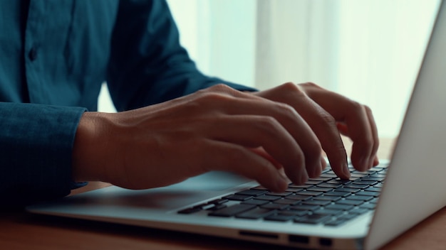 Businessman hand works on capable laptop computer at office table close up shot