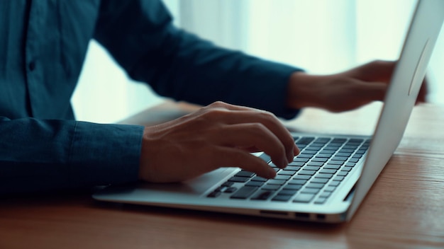 Businessman hand works on capable laptop computer at office table close up shot