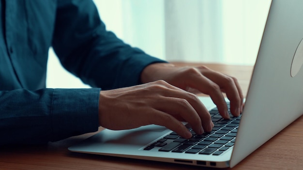 Businessman hand works on capable laptop computer at office table close up shot