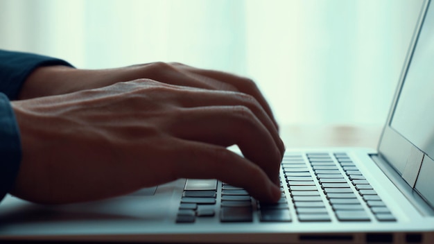 Businessman hand works on capable laptop computer at office table close up shot