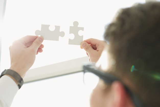 Businessman hands connecting puzzle pieces representing the merging of two companies or joint venture partnership Mergers and acquisition concept