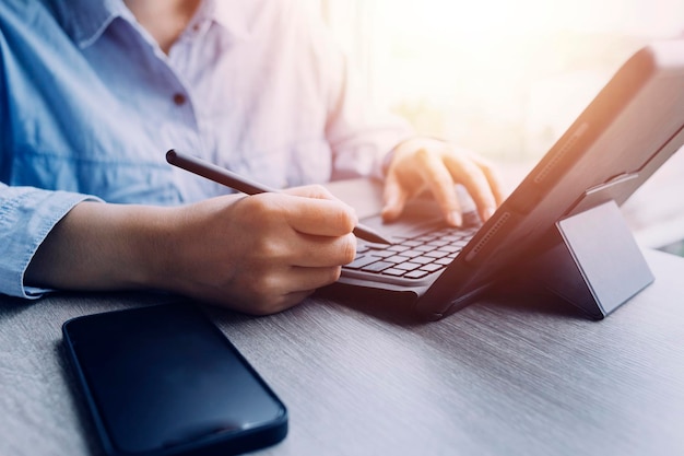 Businessman hands working with finances about cost and calculator and laptop with tablet smartphone at office in morning light