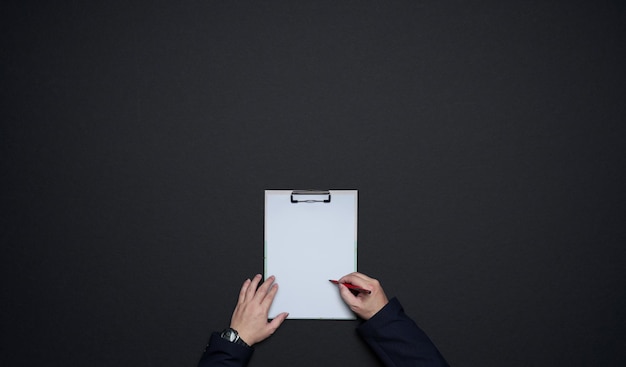 Businessman hands writing on white paper . Flat lay and top view with copy space on black background .business desk  lifestyle concept.