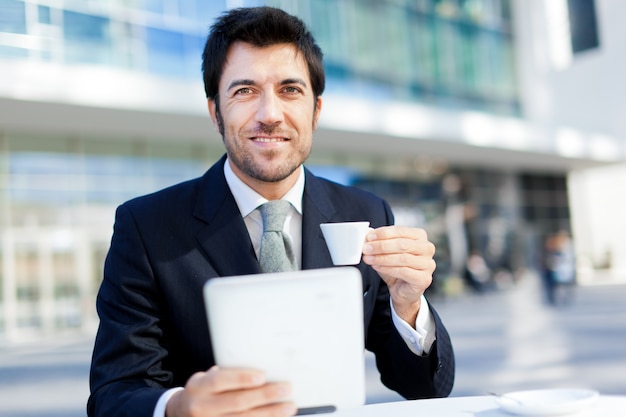 Businessman having breakfast and reading his tablet