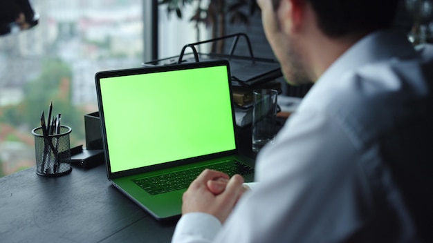 Businessman having video call on laptop with mockup at remote workplace