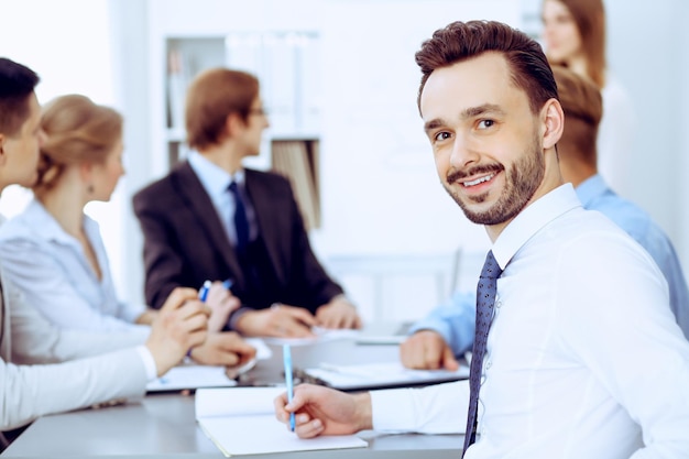 Businessman headshot against a group of business people at a meeting or negotiation in office