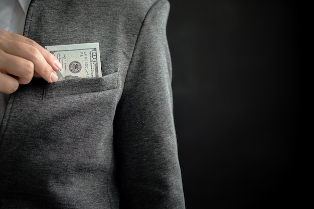 Businessman hiding money bill in pocket