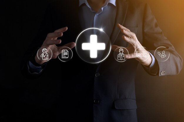 Businessman hold virtual plus medical network connection icons. Covid-19 pandemic develop people awareness and spread attention on their healthcare.Doctor,document,medicine,ambulance,patient icon.