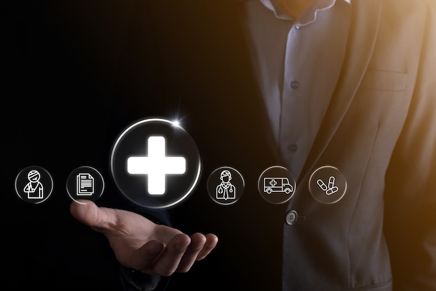 Businessman hold virtual plus medical network connection icons. Covid-19 pandemic develop people awareness and spread attention on their healthcare.Doctor,document,medicine,ambulance,patient icon.