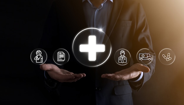 Businessman hold virtual plus medical network connection icons. Covid-19 pandemic develop people awareness and spread attention on their healthcare.Doctor,document,medicine,ambulance,patient icon.