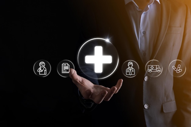 Businessman hold virtual plus medical network connection icons. Covid-19 pandemic develop people awareness and spread attention on their healthcare.Doctor,document,medicine,ambulance,patient icon.