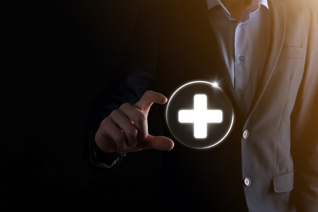 Businessman hold virtual plus medical network connection icons. Covid-19 pandemic develop people awareness and spread attention on their healthcare.