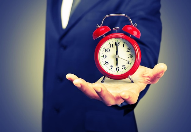 Businessman holding alarm clock in hand