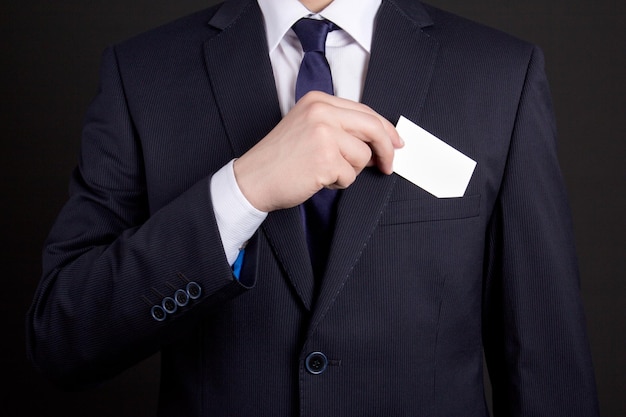 Businessman holding blank visiting card out of his suit pocket