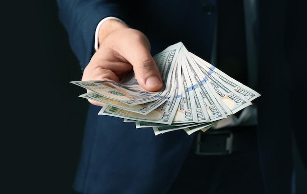 Businessman holding bribe on black background