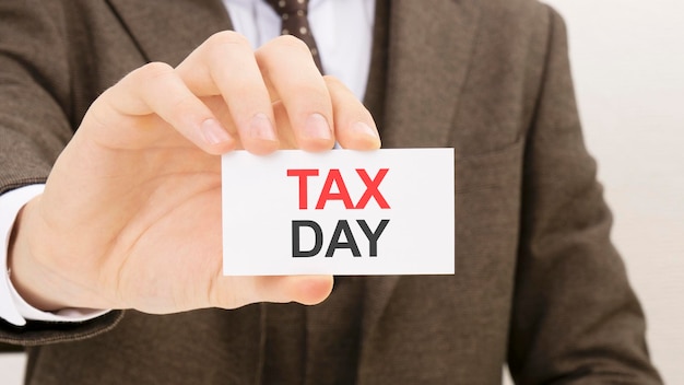 Businessman holding a card with text TAX DAY