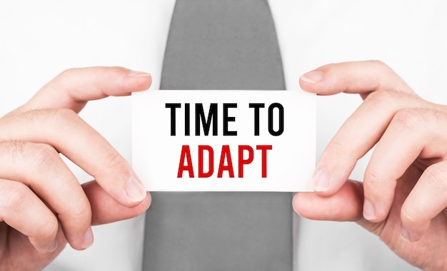 Photo businessman holding a card with text time to adapt ,business concept