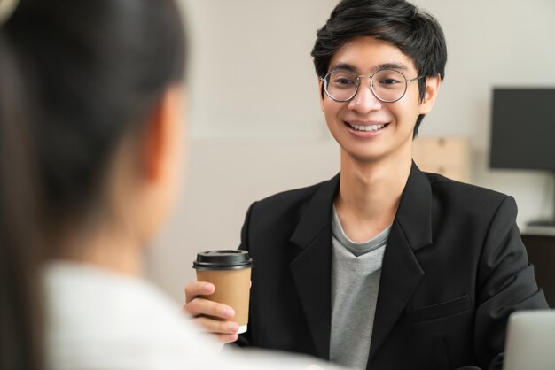 Businessman holding coffee cup and smiling while talking