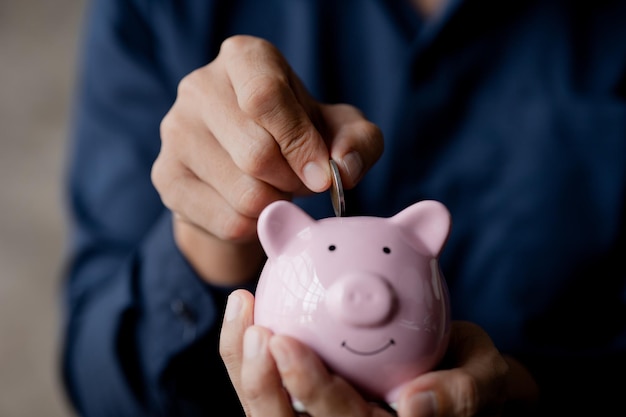 A businessman holding a coin in a piggy bank Placing coins in a row from low to high is comparable to saving money to grow more The concept of growing savings and saving by investing in stock funds