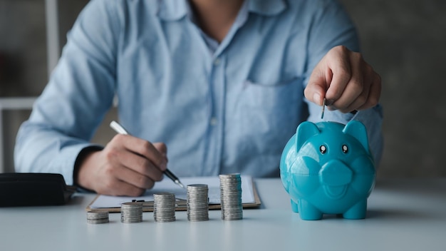 A businessman holding a coin in a piggy bank Placing coins in a row from low to high is comparable to saving money to grow more The concept of growing savings and saving by investing in stock funds