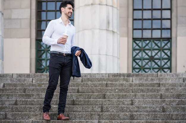 Businessman holding a cup of coffee on his way to work outdoors