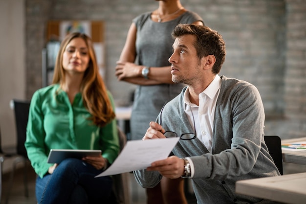 Businessman holding a document and asking questing while attending a meeting in the office