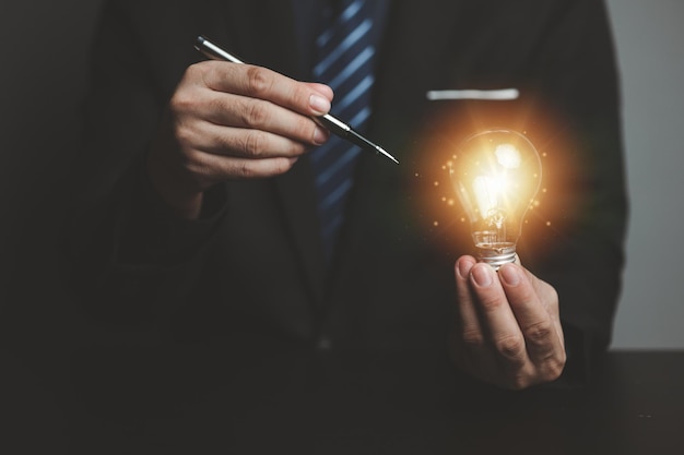 Businessman holding glowing lamp Creative new idea Innovation brainstorming strategizing to make the business grow and be profitable Concept execution strategy planning and profit management