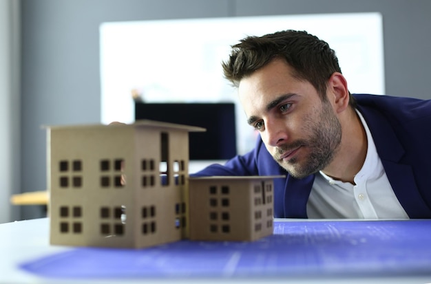 Businessman holding house miniature on hand standing in office