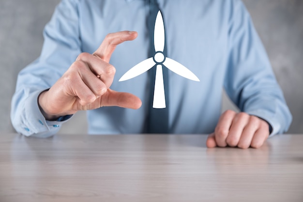 Businessman holding an icon of a windmill that produces environmental energy