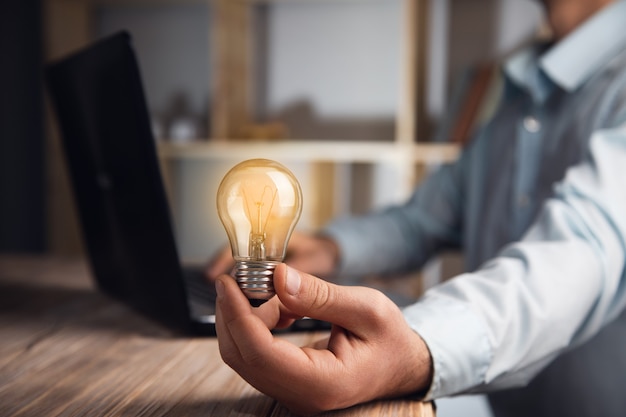 Businessman holding lightbulb with using laptop computer