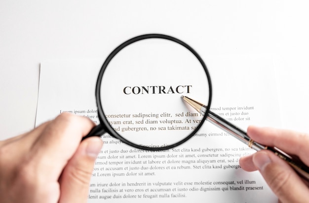 Businessman holding magnifying glass zoom and analyzing contract