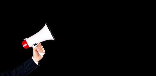 Businessman holding megaphone on empty black background close up