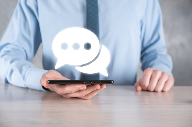 Businessman holding a message icon, bubble talk notification sign in his hands. Chat icon, sms icon, comments icon, speech bubbles