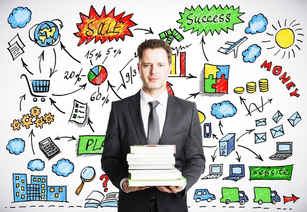 Businessman holding a pack of books with business strategy concept on the background