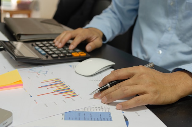 Businessman holding pen to look at business, financial, tax, budget analysis and marketing documents.