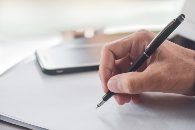 Businessman holding pen writing on paper document working,Close up hand write paperwork