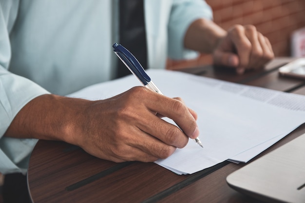 Businessman holding pen and writing on papers