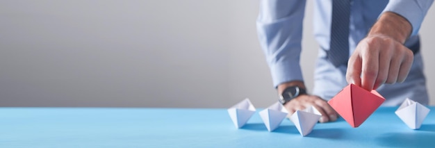 Businessman holding red origami paper boat with a white boats Business Leadership