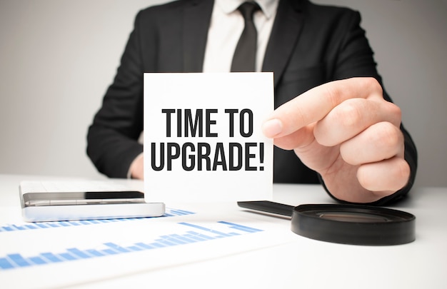 Businessman holding sheet of paper with a message Time to upgrade