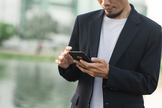 Businessman holding smartphone outdoor city park urban