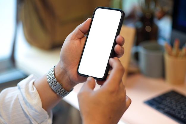 Businessman holding smartphone, using smartphone at his office desk. phone blank screen. close-up